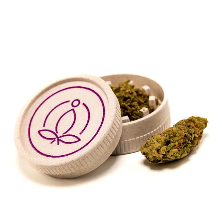 Ein Grinder neben Cannabisblüten